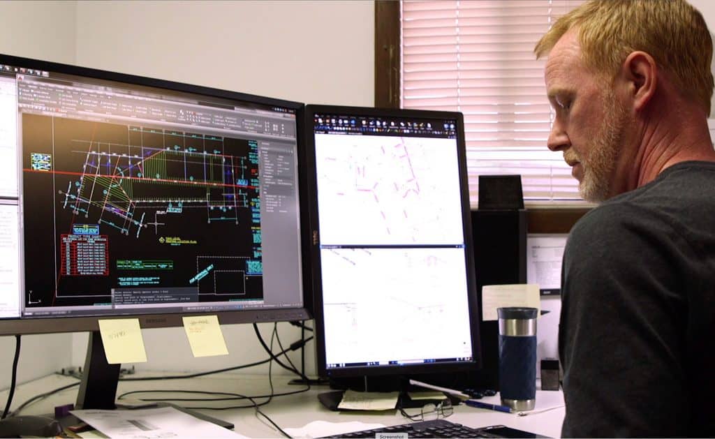 A RedBuilt employee works diligently at a computer, looking down while taking notes