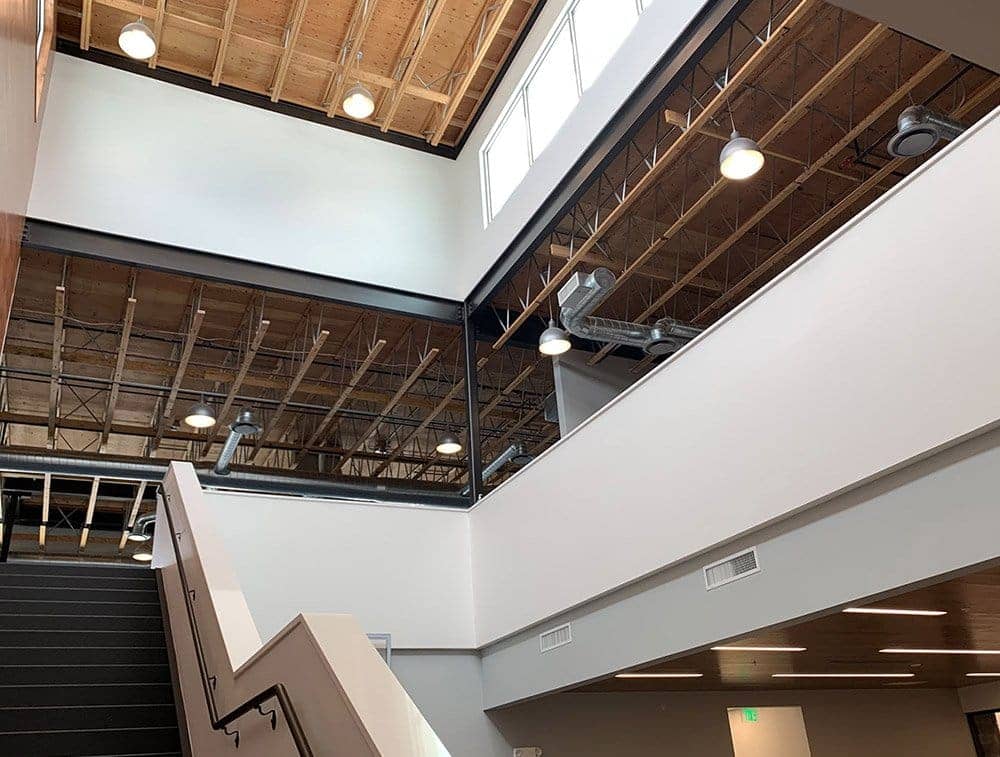 Trusses are exposed throughout a space with stairs leading up to another floor