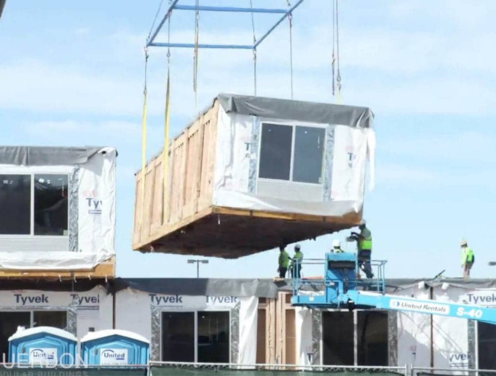 A modular unit made during offsite construction is lowered onto a site