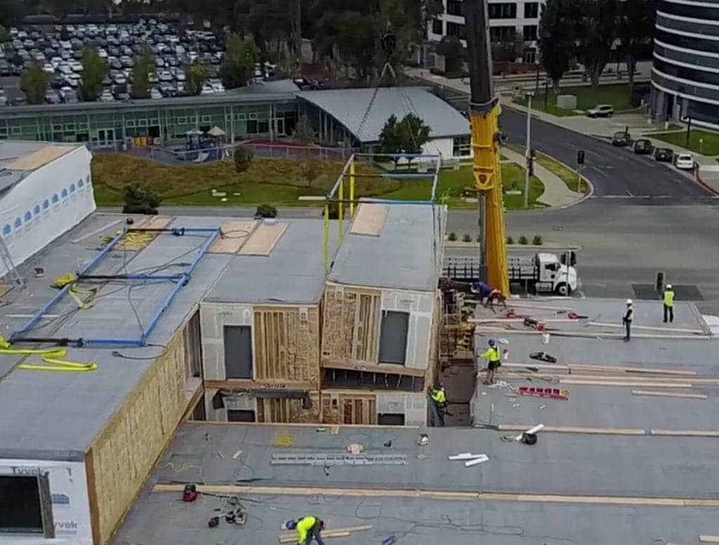 Overview shot of a crane lowering a unit made during offsite construction