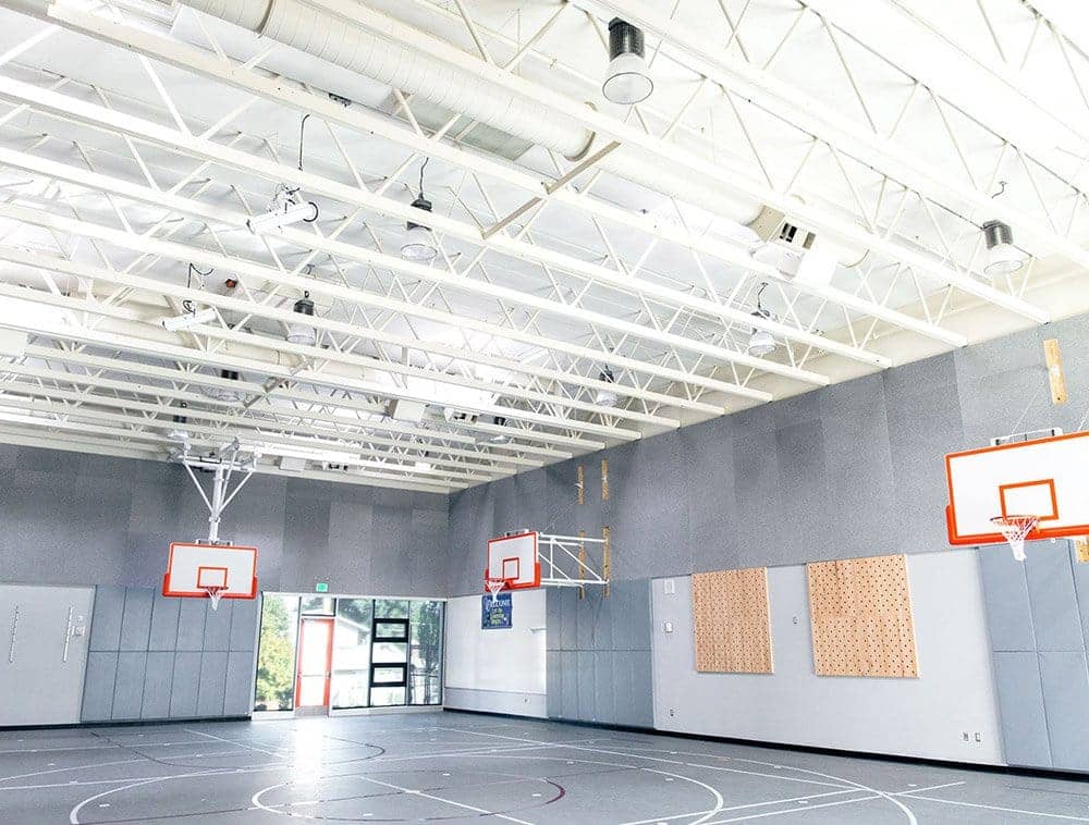 A basketball court featuring white trusses overhead