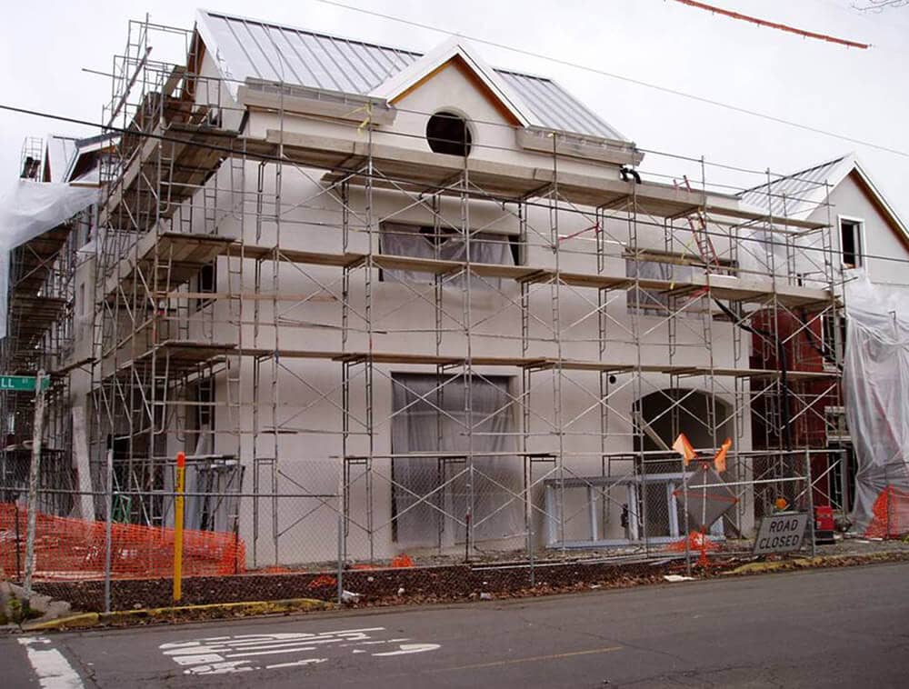 A construction site next to a street with rows of scaffolds and planks by a building