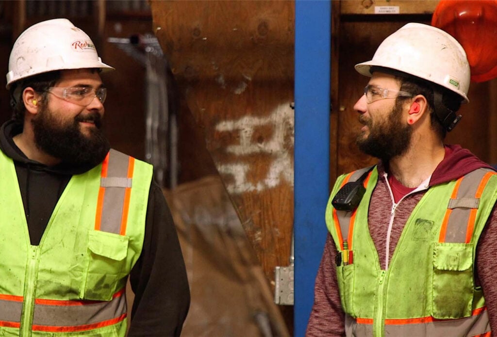 image of two associates in a manufacturing plant smiling at eachother